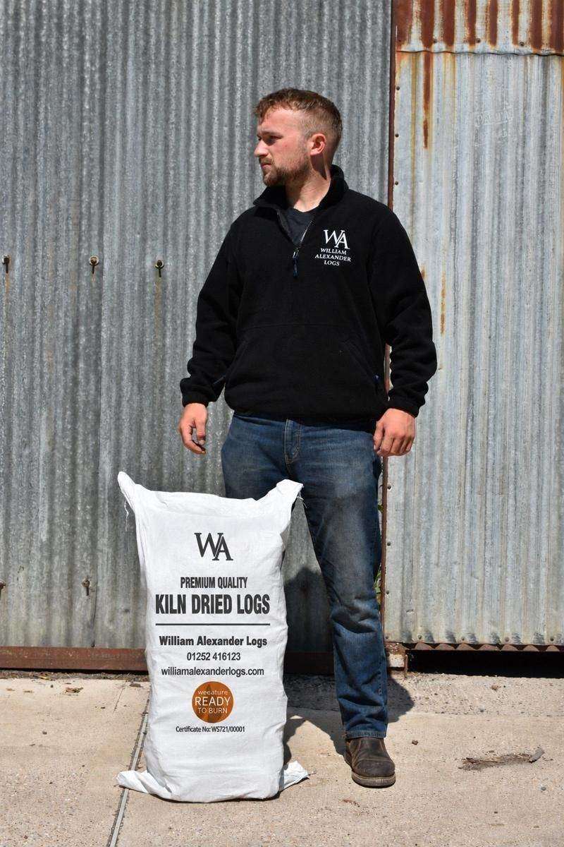 One of the William Alexander team standing at the yard with a bag of kiln-dried logs